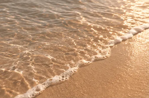 Une vague vient doucement mourir sur le sable doré